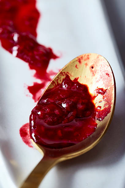 istock Raspberry sauce on gold spoon with streak on white tray 2216182961