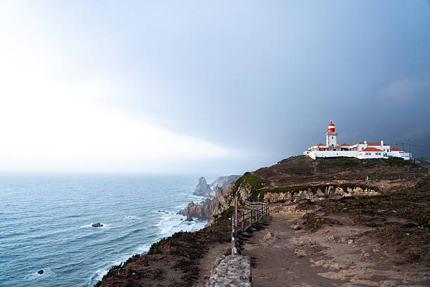 Rugged cliff path leading to Cabo da Roca lighthouse as daylight fades over the Atlantic