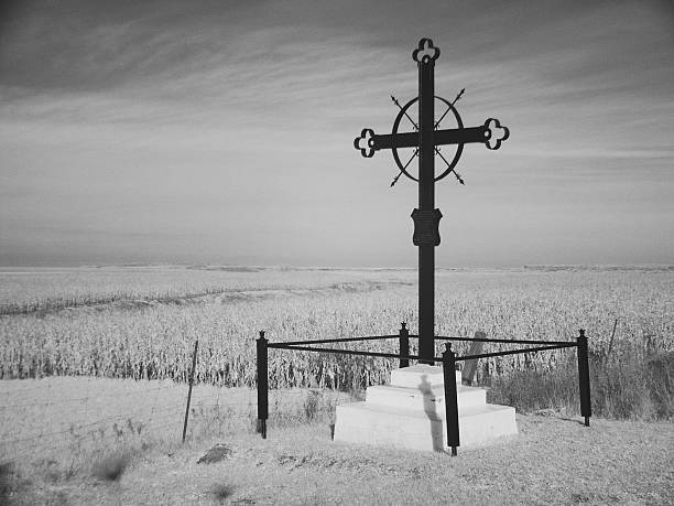 A silhouette of a cross against a dramatic blue sky, high in the French Alps