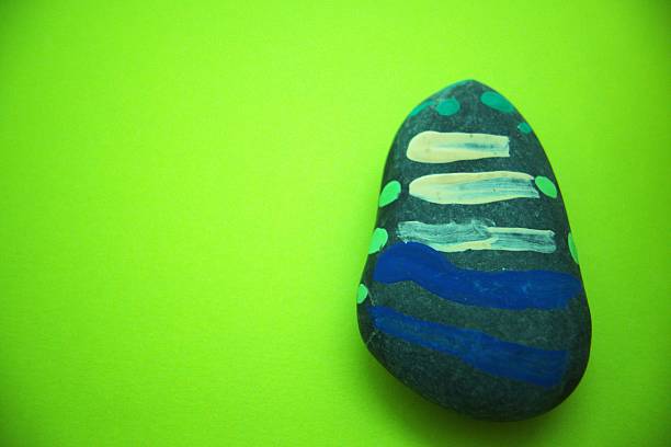 Painted pebble with green background