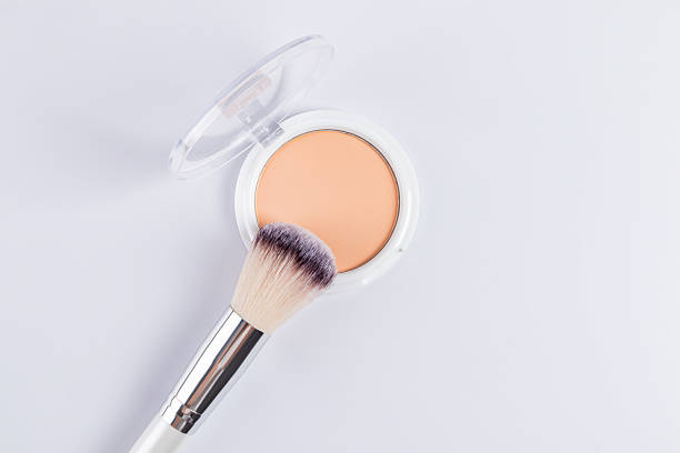 istock An open white pack of compact powder in a natural tone on a white background, a beautiful fluffy makeup brush. top view. copy space. product texture. 2216197668