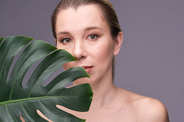 istock Young caucasian female with monstera leaf against gray background looking 2216199261