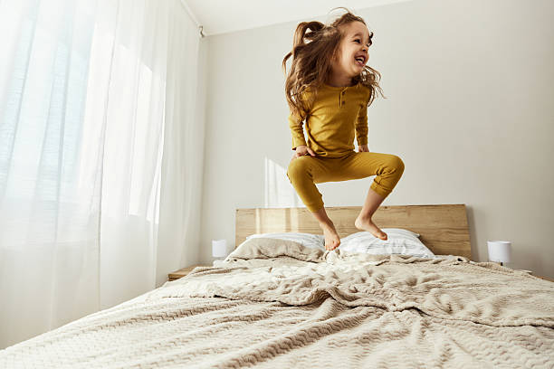 istock Carefree girl having fun while jumping on a bed. 2216201069