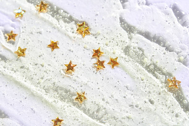 Golden star confetti on shimmery white texture with glitter and bubbles creating