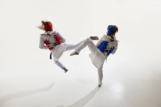 Competitive young women, taekwondo athletes in motion, practicing kicks and defense stances on white background. Concept of martial arts, t counterattack, combat sport, agility, technique, reaction