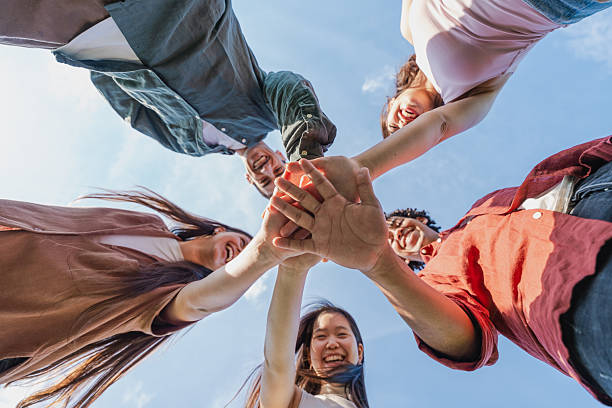 istock Multiethnic group of young friends stacking hands outdoors 2216210184