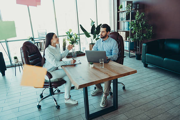 istock Professional colleagues discussing project ideas at workspace desk in modern office interior with large windows 2216210795