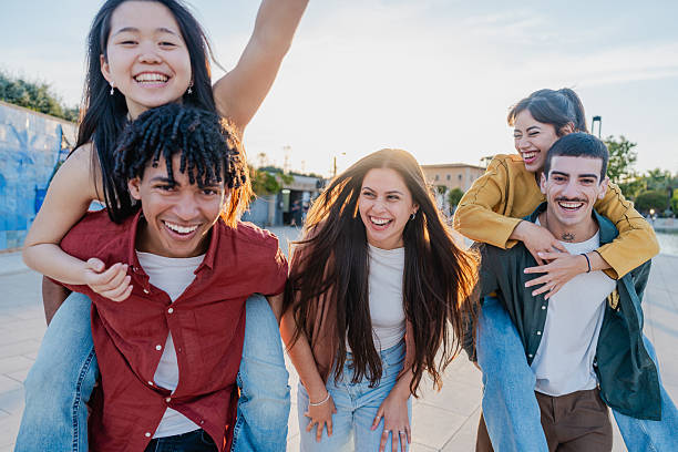 istock Diverse young friends laughing and playing outdoors at sunset 2216211550