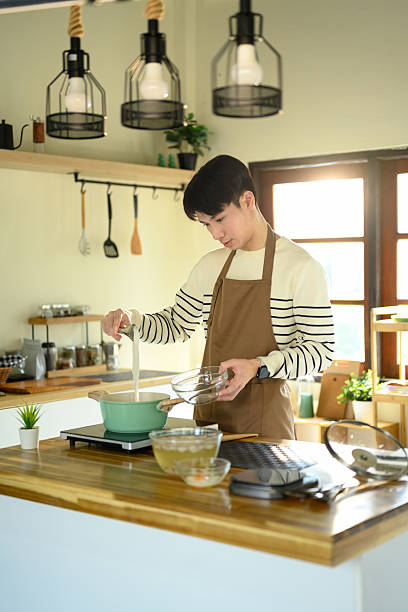 istock Man in apron pouring ingredients into a pot while preparing a homemade meal 2216212667