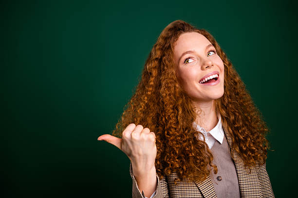 istock Cheerful professional woman gesturing confidently with thumb on green background, expressing joyful attitude and stylish elegance 2216212723
