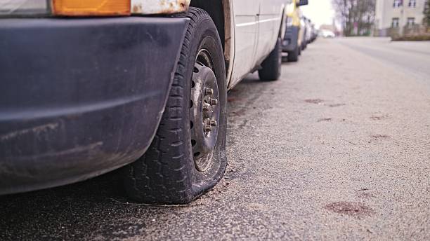 istock Car with Flat Tyre Parked by Street Curb 2216213176