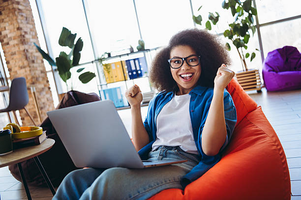 istock Young professional woman inside casual office space using a laptop while celebrating a success 2216216319