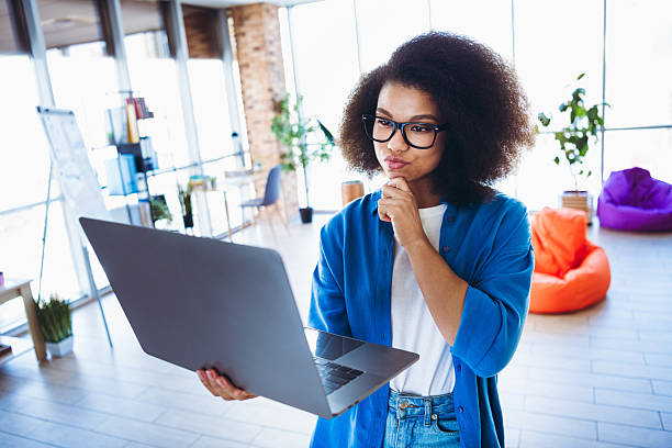 istock Young woman in a modern office analyzing a laptop screen while considering business strategies wearing casual attire 2216216325