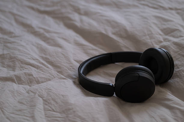 istock Black wireless headphones lying on beige bedding in natural light. 2216216473