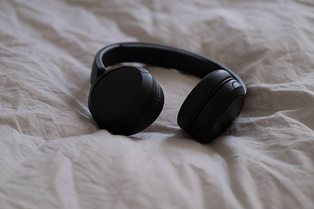 istock Black wireless headphones lying on beige bedding in natural light. 2216216612