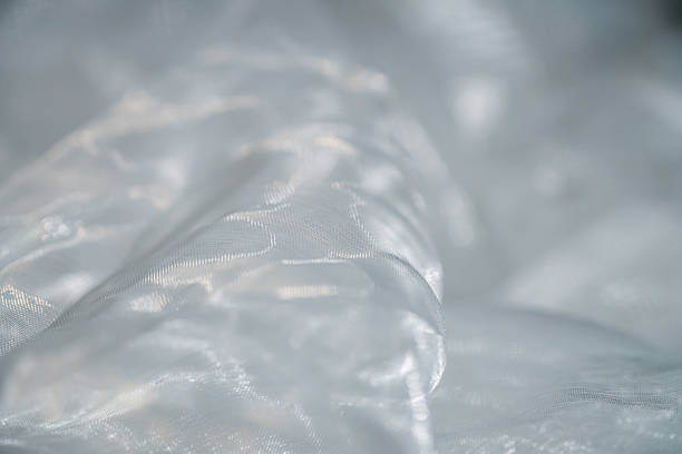 A photograph captures intricate mesh fabric patterns adorned with sparkling water droplets. Macro
