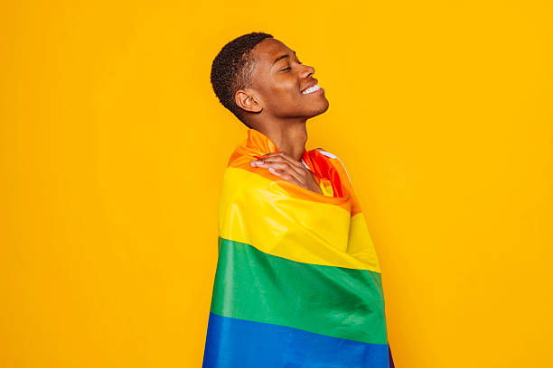 istock Young man embracing rainbow flag celebrating lgbtq+ pride on yellow background 2216223421