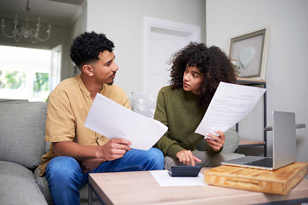 istock Couple Sitting Together Discussing Financial Documents at Home with a Laptop 2216223480