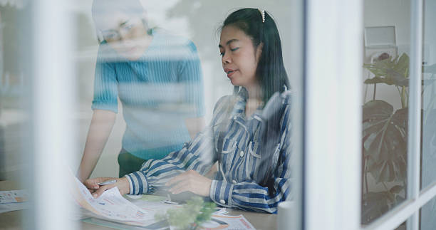 istock Two coworkers discuss business documents and goal-oriented planning in a modern office. 2216223644
