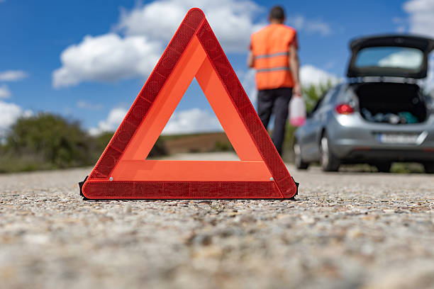 istock Warning triangle on the road with broken car and driver 2216229208