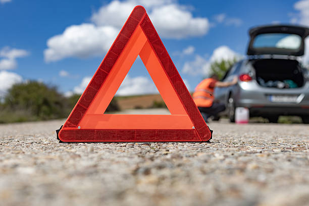 istock Red warning triangle on the road with broken car and mechanic 2216229263