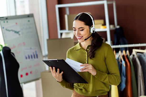 istock Fashion designer working in studio with clipboard and headset, surrounded by workshop details and planning charts 2216230307
