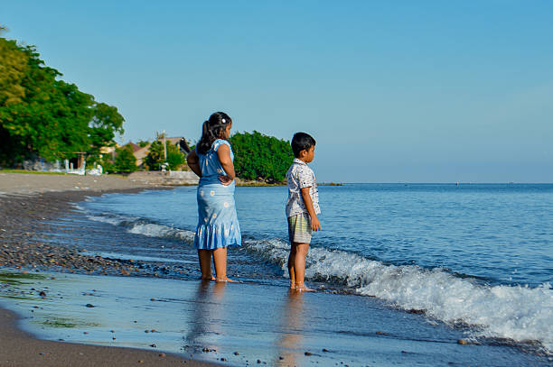 istock Two young children watching ocean waves from beachside 2216230339