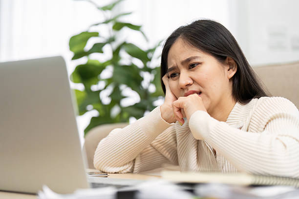 istock Challenges and Work Stress. A woman contemplates over her laptop, reflecting the challenges of remote work. 2216230611