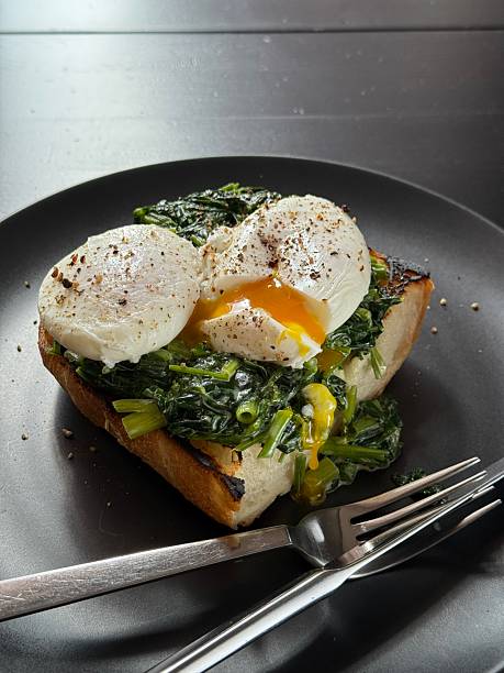 Poached egg on a piece of bread with spinach on the black plate
