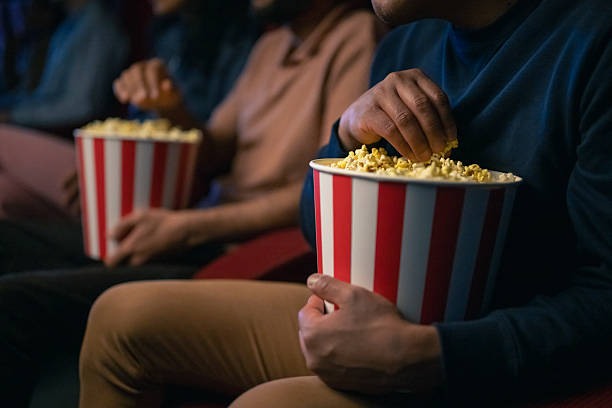 istock Close-Up of Hands Enjoying Popcorn in a Dimly Lit Cinema Setting 2216230805