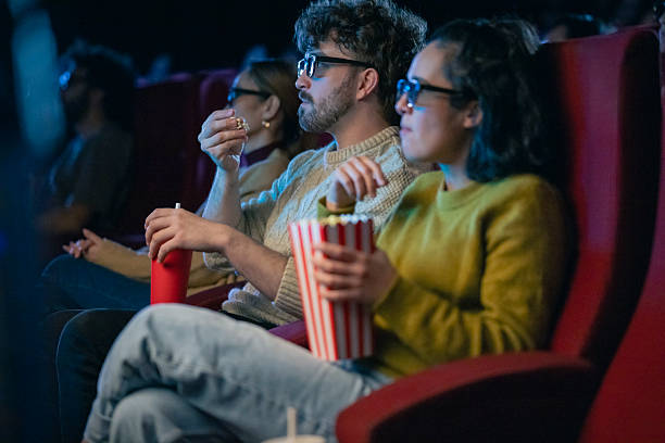 istock Young Hispanic Couple Enjoying 3D Cinema Experience with Popcorn and Drinks in Dim Lighting 2216230833