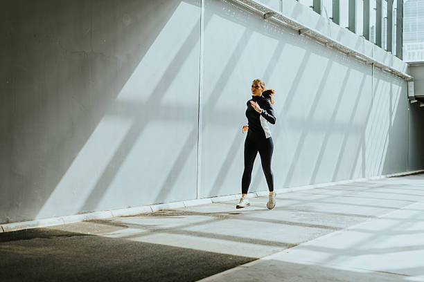 istock Jogger dashes along a sunlit pathway, shadows stretching across the ground in a bustling urban setting 2216233295