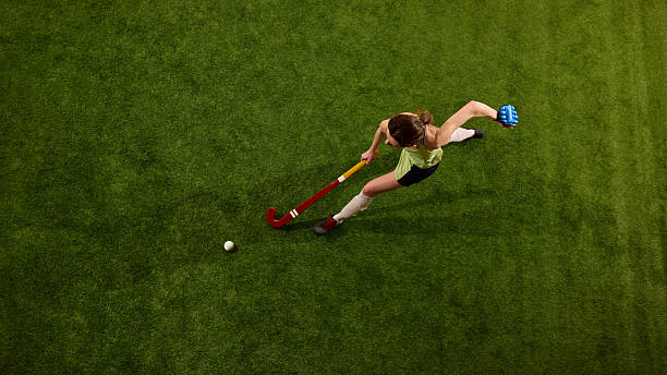 istock Hockey player drives forward in full stride on green grass field against white studio background, symbolizing control and power. 2216235736