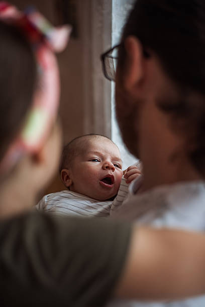 istock Newborn baby yawning while being held by parents 2216237743