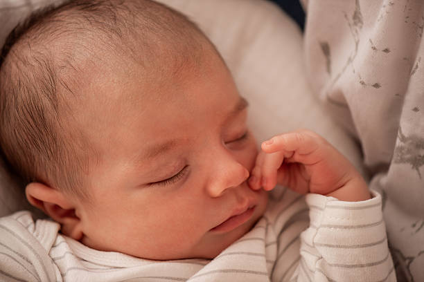 istock Peaceful Newborn Baby Sleeping in Striped Outfit 2216240102