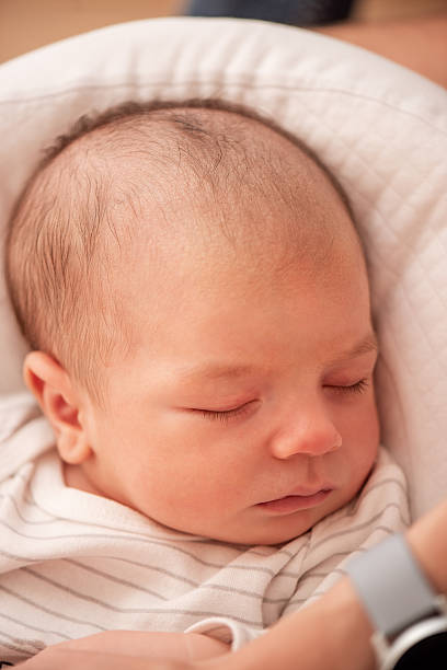 istock Newborn baby sleeping peacefully in mother's arms 2216240105