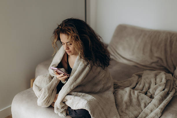 istock Young Woman Relaxing on a Sofa While Using a Smartphone 2216240310