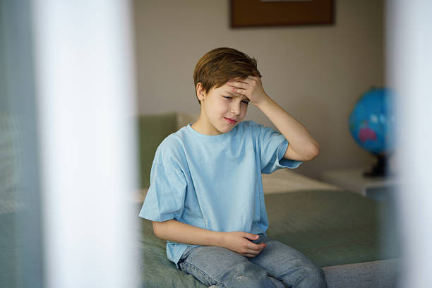 istock Boy with a headache is sitting on the bed 2216241363