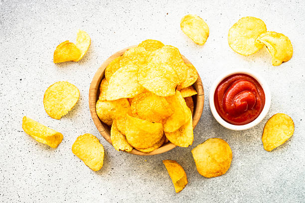 istock Potato chips in wooden bowl on white table. Top view. 2216242829