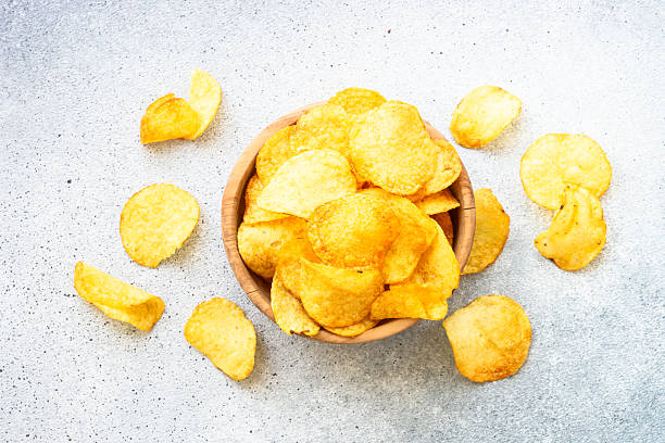 istock Potato chips in wooden bowl on white table. Top view. 2216242831
