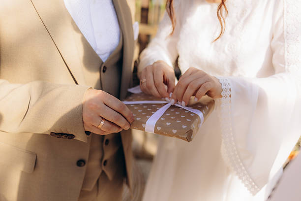 istock Bride and Groom Holding Heart-Patterned Wrapped Gift at Wedding Celebration 2216247621