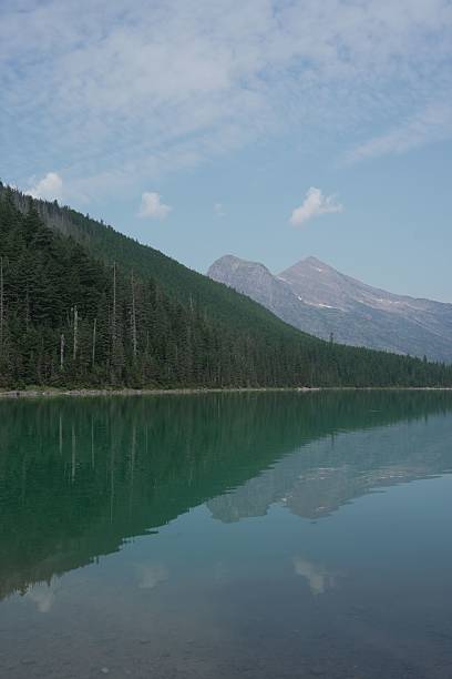 istock Serene lake reflecting a forest and mountain under a partly cloudy sky, showcasing natural beauty 2216248081