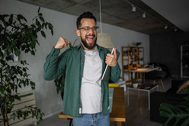 istock Excited freelancer celebrating success with digital tablet at home 2216251730