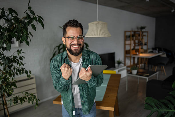 istock Excited young man celebrating success with digital tablet at home 2216251731