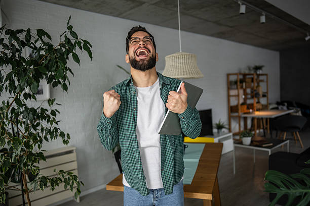 istock Excited young man celebrating success working remotely from home 2216251734
