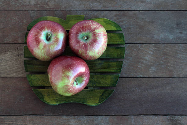 Fresh,three apples on the green color shaped apple wooden board. Top view