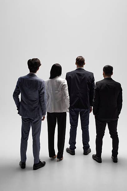 istock Back view photo of professionals stand looking forward against white studio backdrop, prepared for business negotiations. 2216257543
