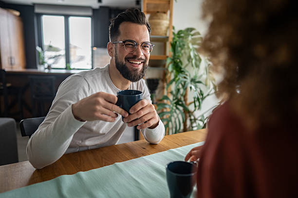 istock Young bearded man smiling and drinking coffee with his partner at home 2216261833