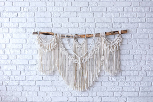 istock Wall panel in style of Boho made of cotton threads using the macrame technique for home decor. Cozy Home decor concept. White Macrame on brick wall in living room with wabi sabi interior design 2216263339