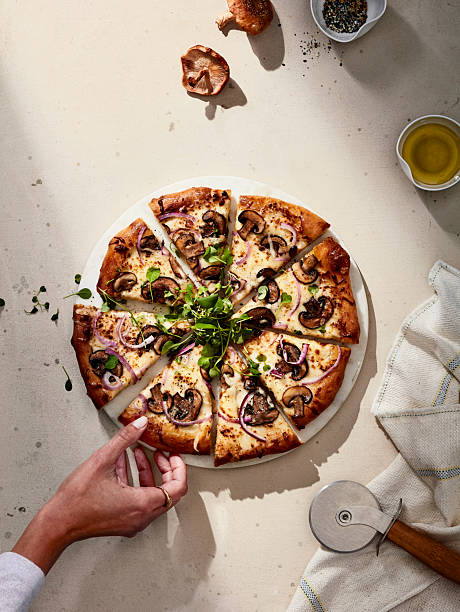 Sliced mushroom pizza with herbs on light stone background